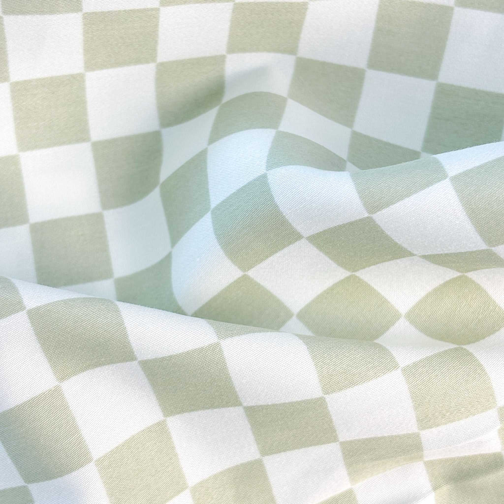 Fitted sheet in sage checker pattern on bed